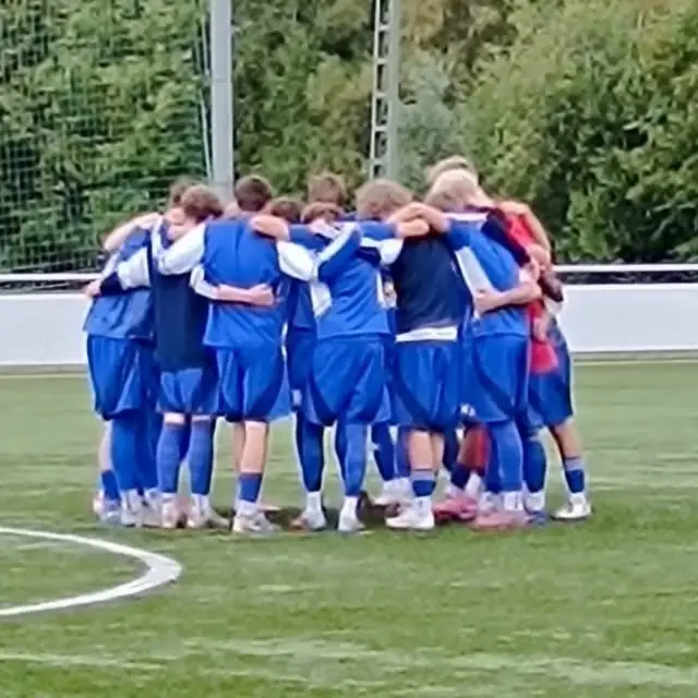 Eine Kickers-Jugendmannschaft steht auf dem Platz im Kreis zusammen